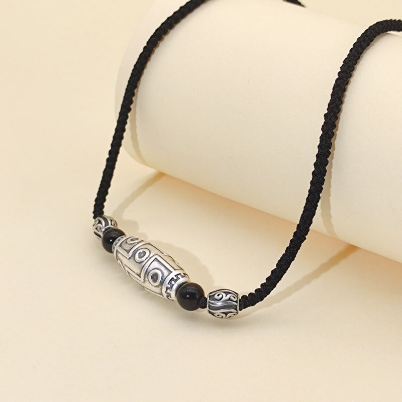 Nine-eye Dzi necklace resting on a cream display