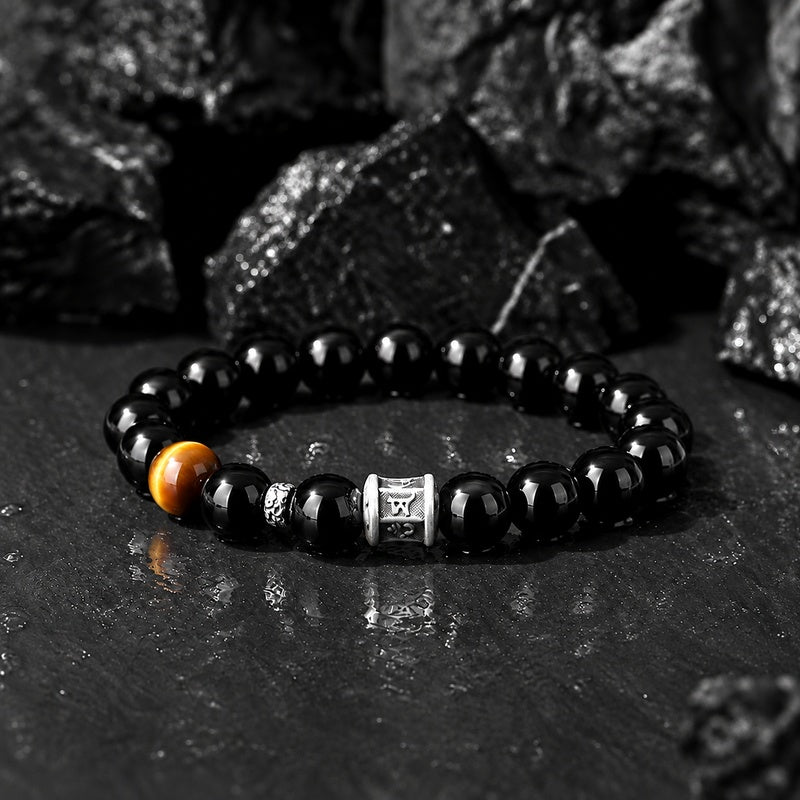Obsidian and tiger eye mantra bracelet on dark rock background