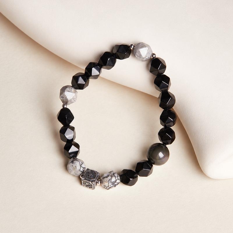 Vertical view of the complete map stone and obsidian bracelet on a cream cushion