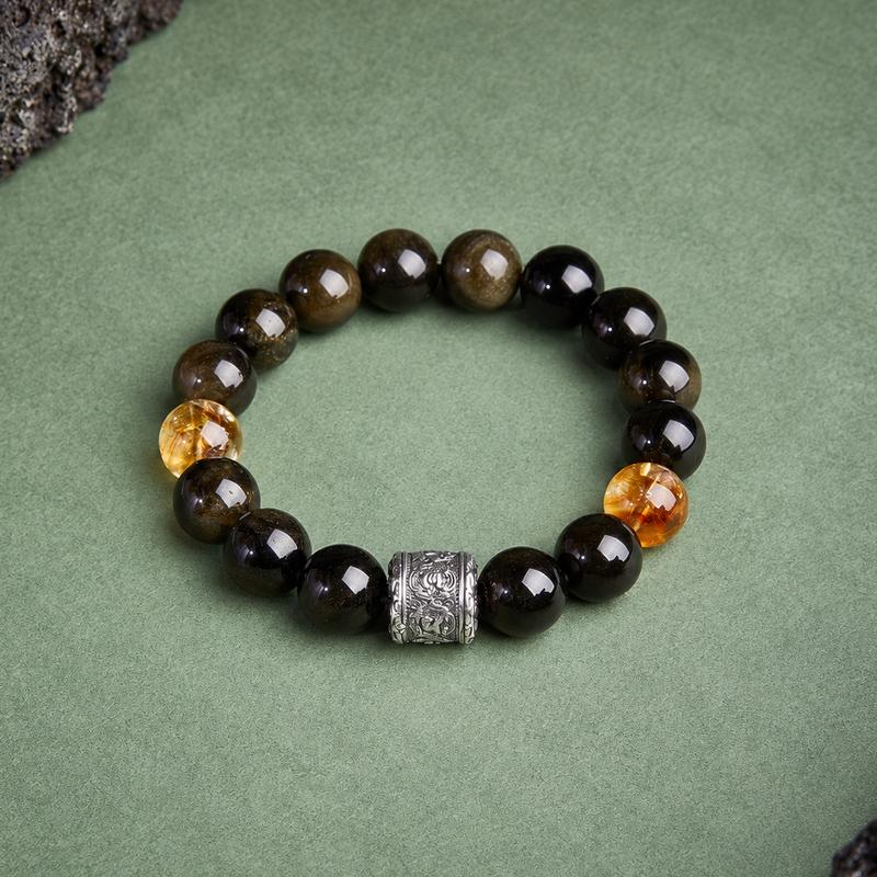 Top view of obsidian bracelet with yellow tower quartz beads and an engraved barrel