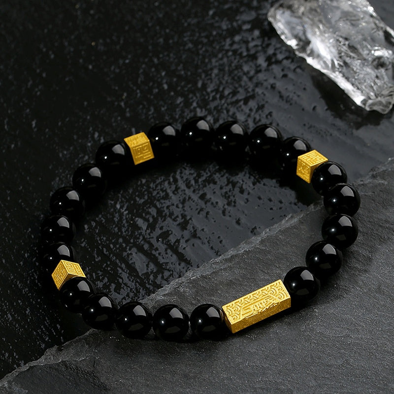 Polished obsidian and engraved gold blessing accents resting on slate