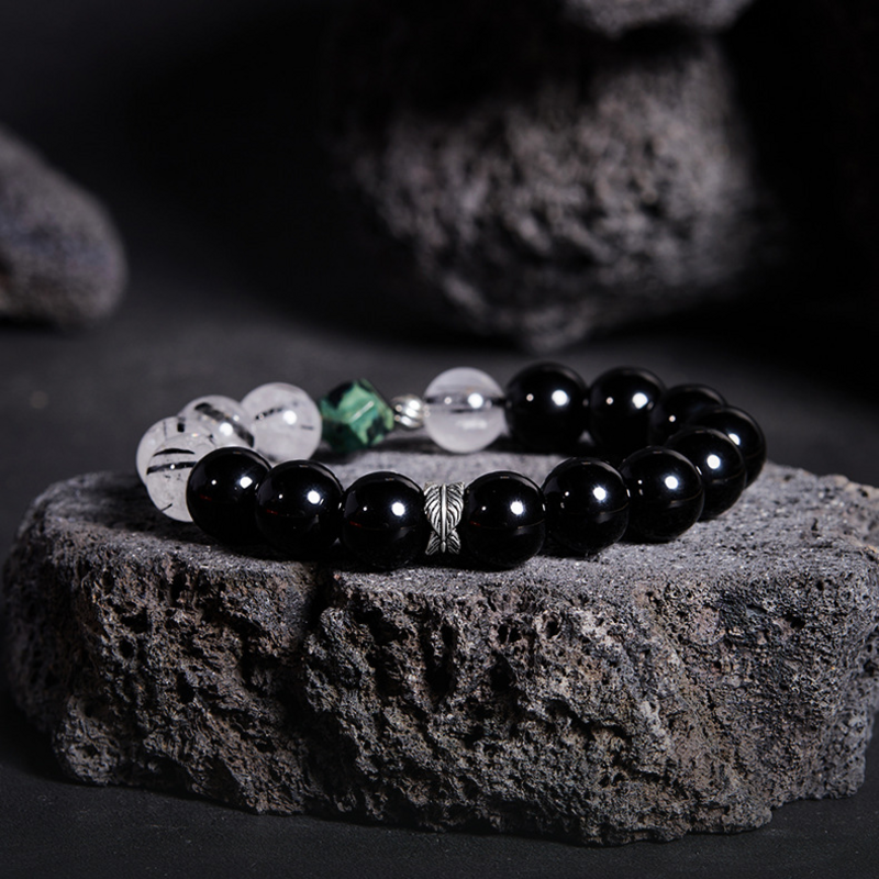 Feather obsidian and black-inclusion quartz bracelet on original dark rock background