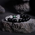 Feather obsidian and black-inclusion quartz bracelet on original dark rock background