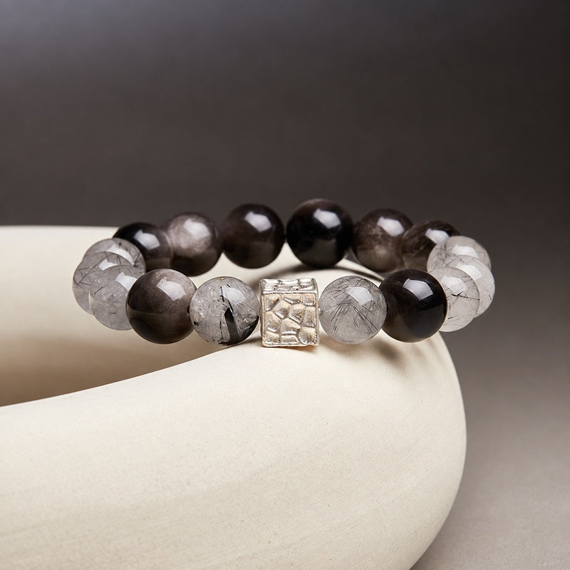 Black inclusion quartz and silver sheen obsidian bracelet on cream ceramic