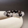 Black inclusion quartz and silver sheen obsidian bracelet on cream ceramic