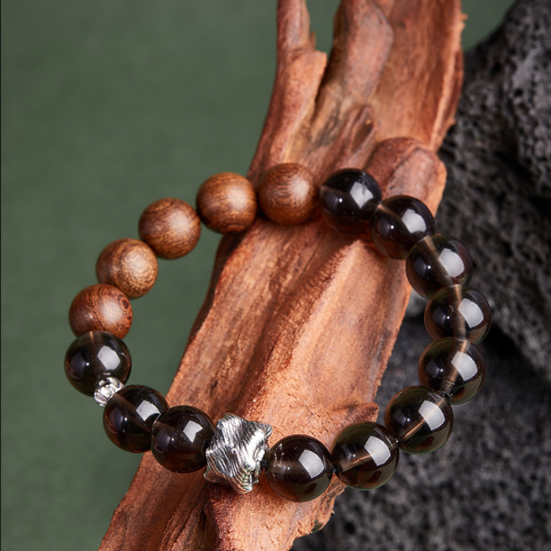Obsidian and golden silk wood bracelet resting on wood