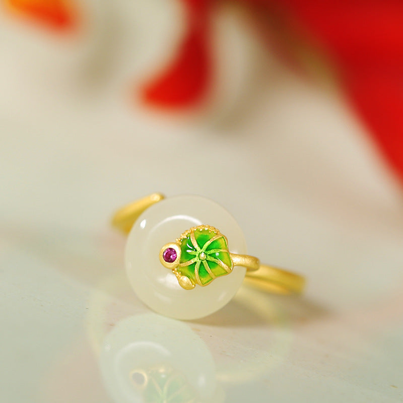 Nephrite jade ring with green enamel lotus leaf on a pale reflective surface