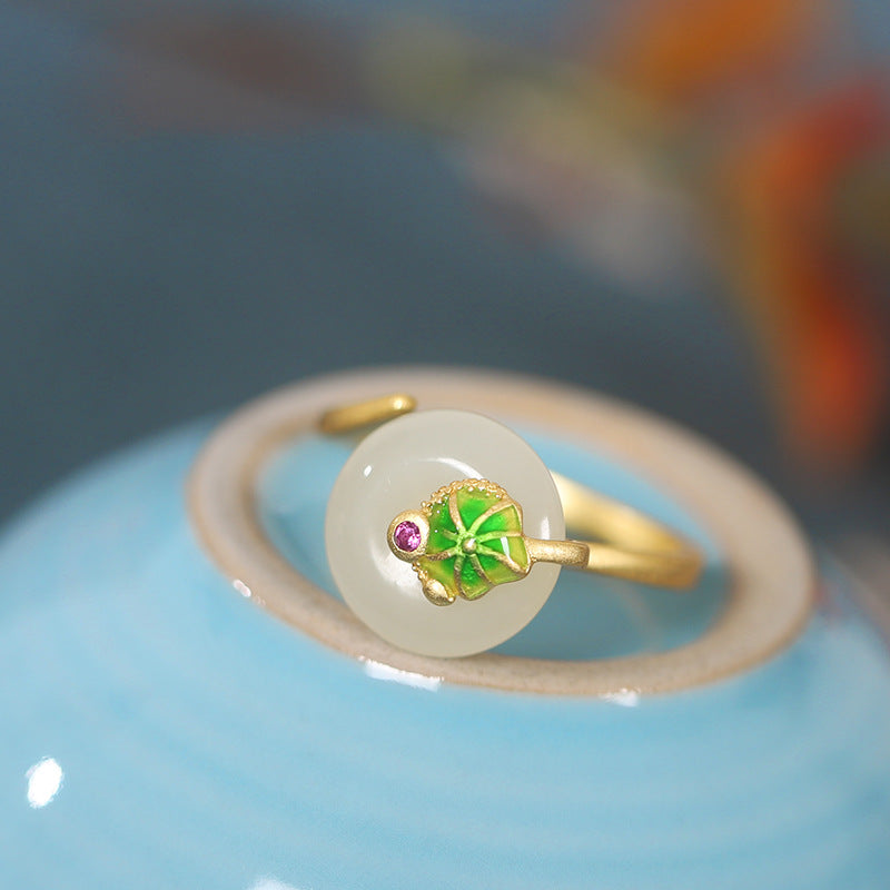 Lotus leaf nephrite jade ring resting on blue ceramic