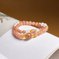 Sunstone and freshwater pearl double-wrap bracelet on an open book with brown background