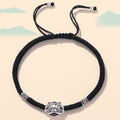 Black braided cord bracelet with an oxidized silver guardian lion face and engraved spacer beads.