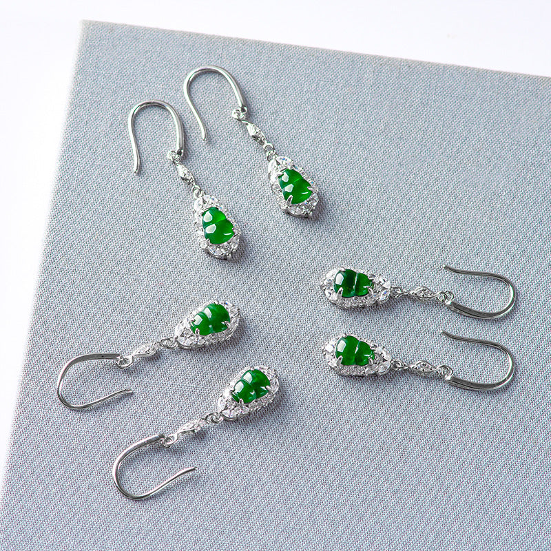Multiple pairs of silver and green jade Wulu earrings arranged on gray fabric