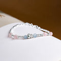 Aquamarine and rose quartz gourd bracelet resting on a book, oblique view