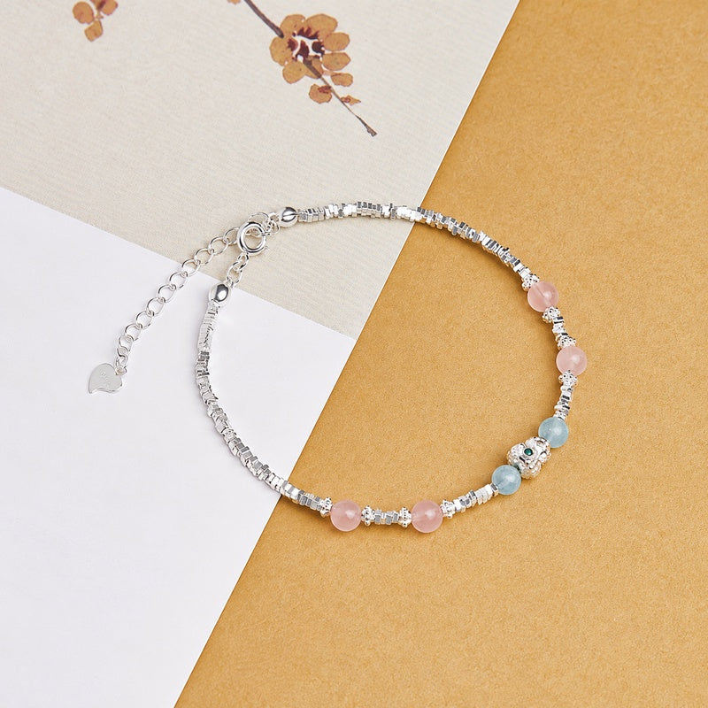Aquamarine and rose quartz bracelet on a book and warm gold fabric