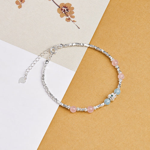 Aquamarine and rose quartz bracelet on a book and warm gold fabric