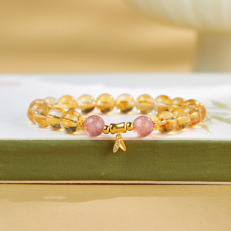 Citrine and pink strawberry quartz bamboo bracelet on a green book