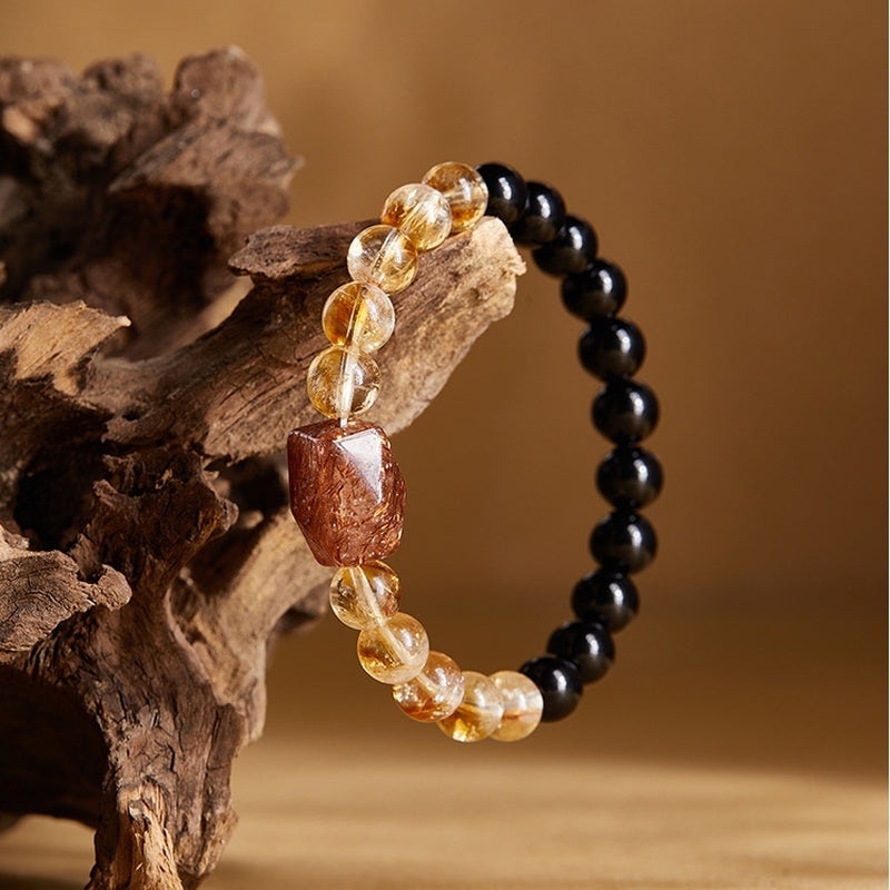 Obsidian and black gold super seven bracelet displayed on wood