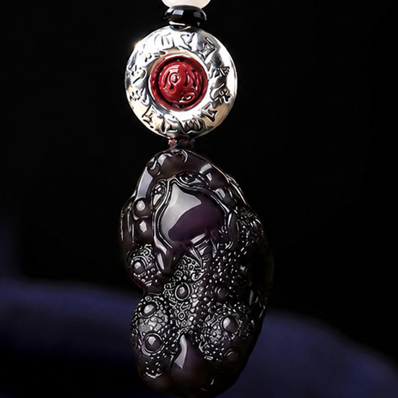 Close detail of obsidian Pixiu and cinnabar medallion