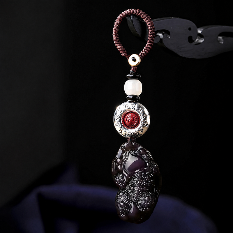 Black obsidian Pixiu auto keychain hanging in dark studio