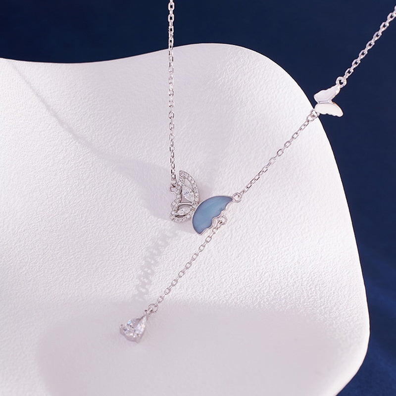 Butterfly necklace with clear cubic zirconia resting on a white display