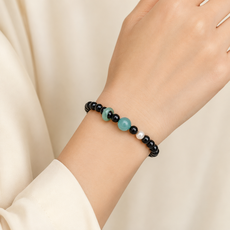 Blue water jade and obsidian bracelet worn on a woman's wrist