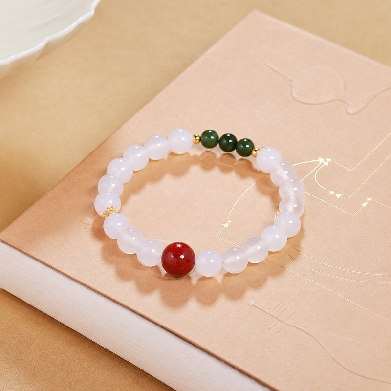 Angled view of red cinnabar and white chalcedony bracelet on a book
