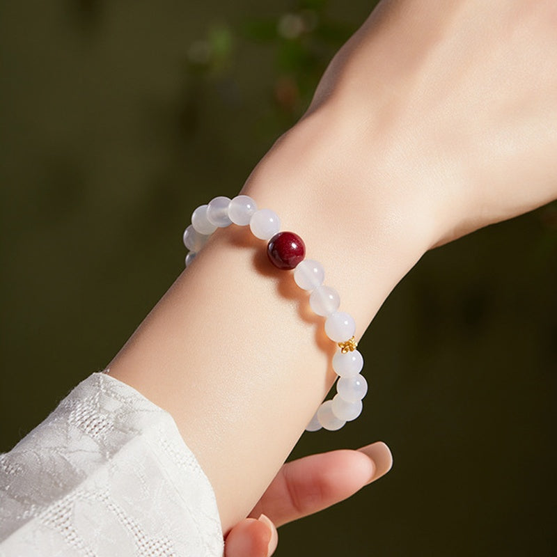 White chalcedony and cinnabar bracelet worn on a wrist with lace sleeve