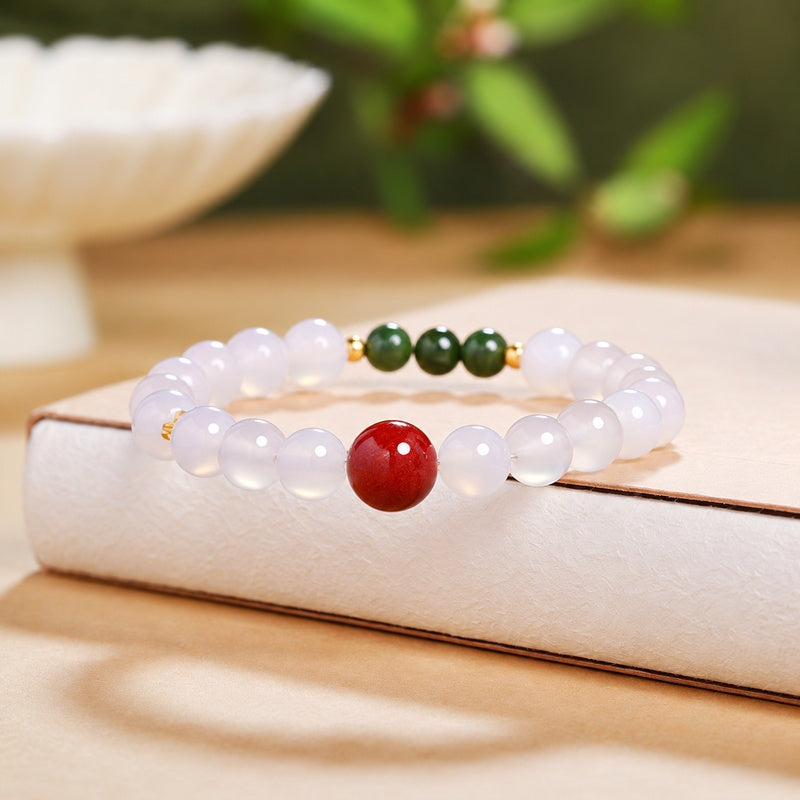 Cinnabar and white chalcedony bracelet resting on a warm book background