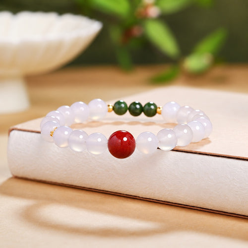 Cinnabar and white chalcedony bracelet resting on a warm book background