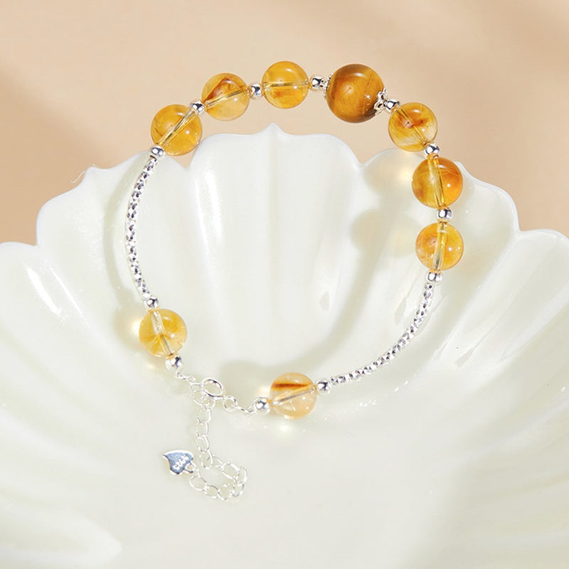 Citrine bracelet and tiger's eye focal bead displayed on a shell dish