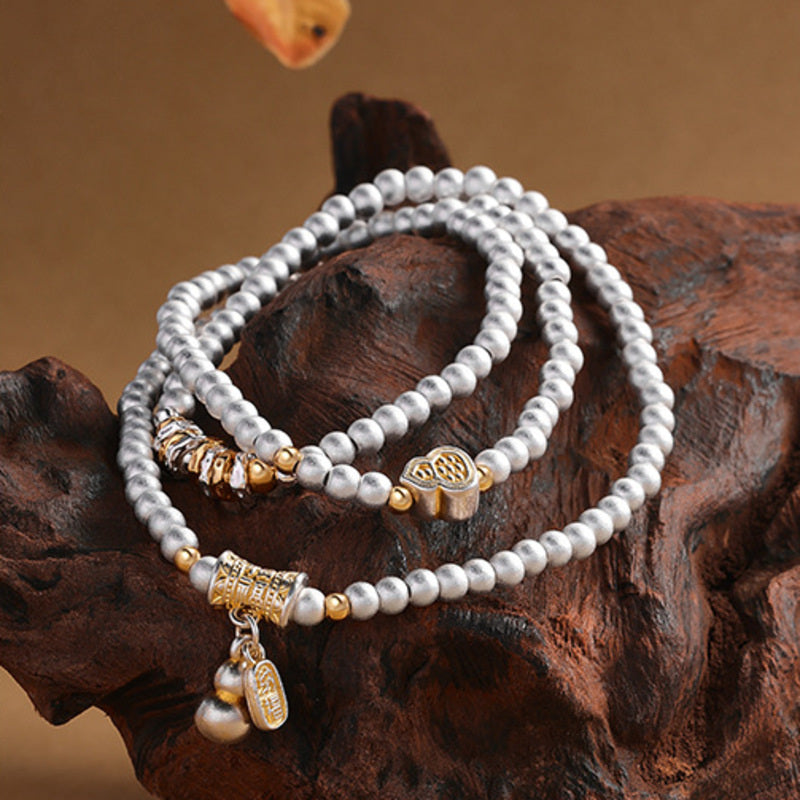 Fine Silver 999 gourd triple-wrap bracelet displayed on driftwood
