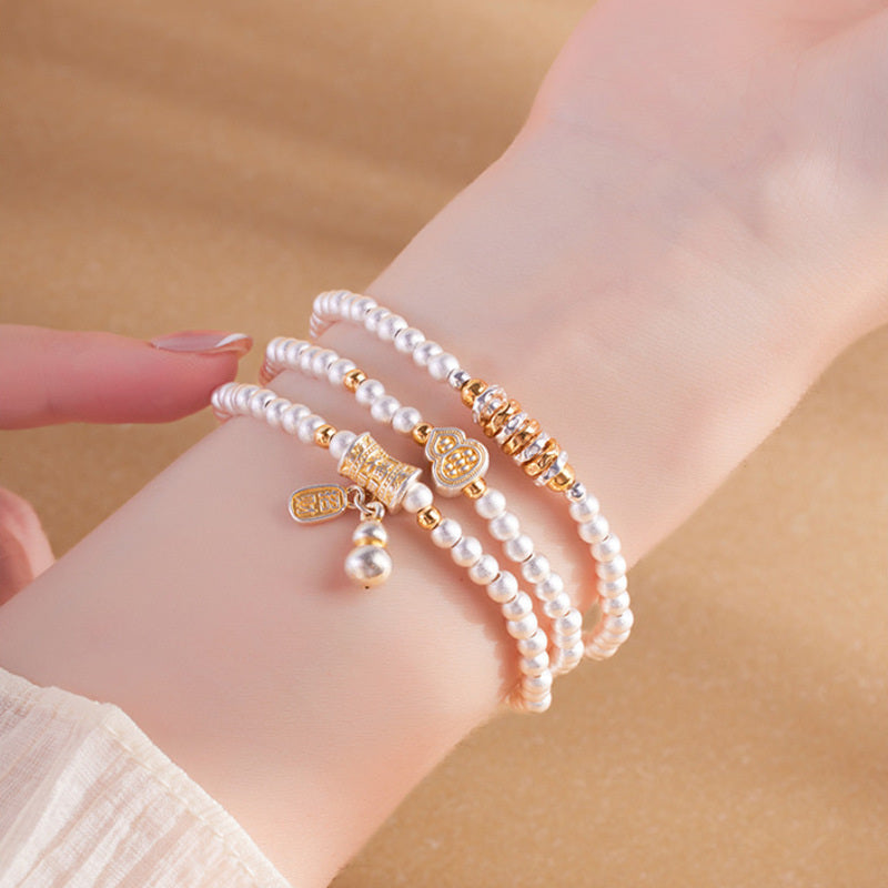 Fine Silver 999 gourd triple-wrap bracelet worn on wrist against sand