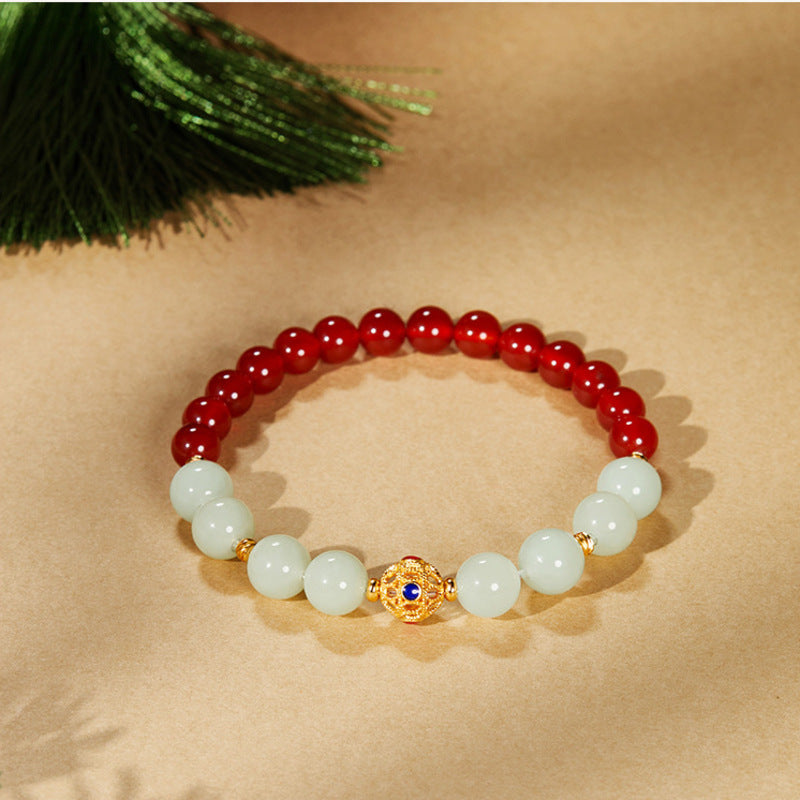 Centered red agate and nephrite jade fortune bead bracelet on warm background