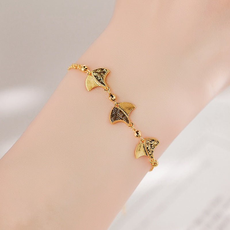 Supplier model wearing the adjustable gold-colored ginkgo bracelet