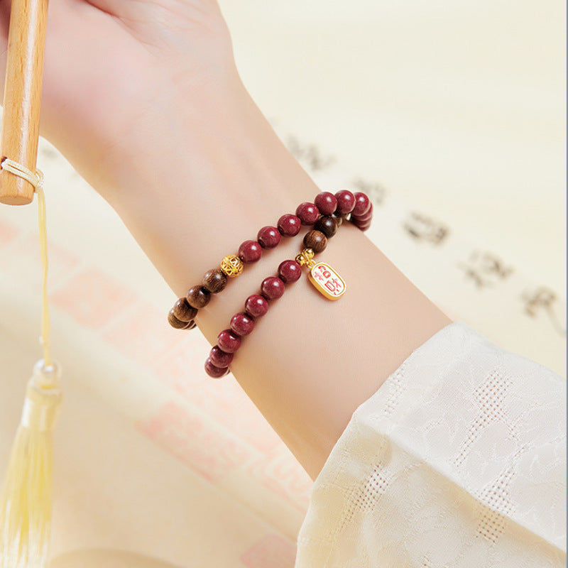 Double-wrap cinnabar and sandalwood bracelet worn on wrist