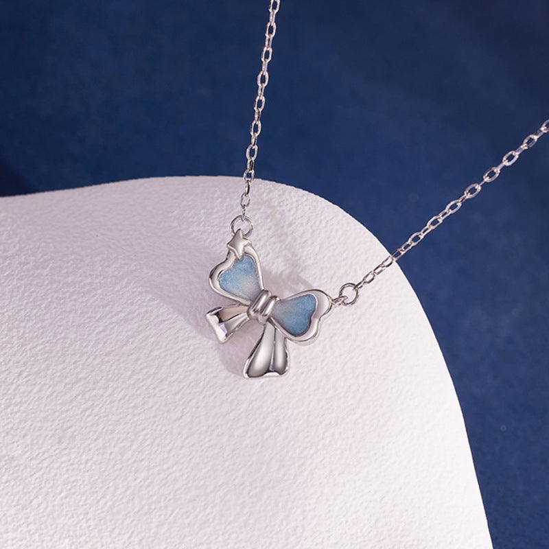 Gradient cold enamel bow pendant detail on white surface