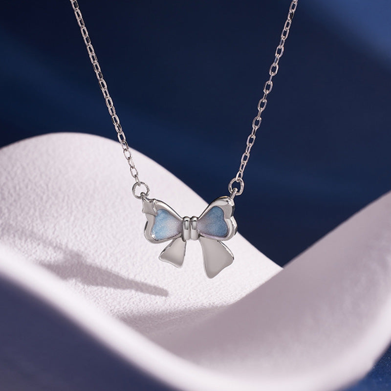 Gradient enamel bow necklace on sculpted white fabric