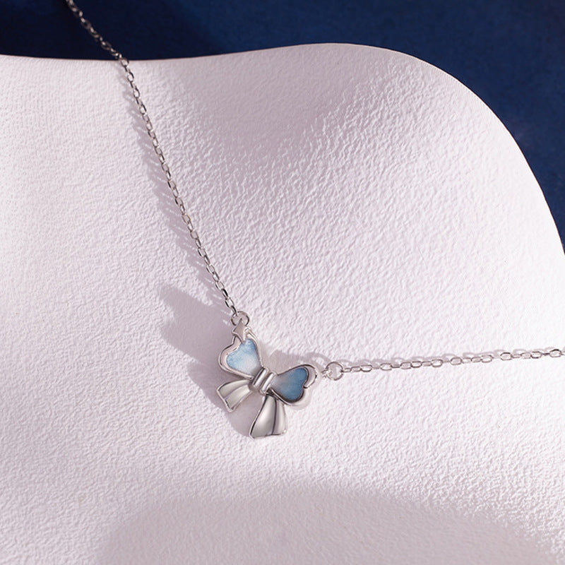 Polished silver bow necklace shown from an angled view