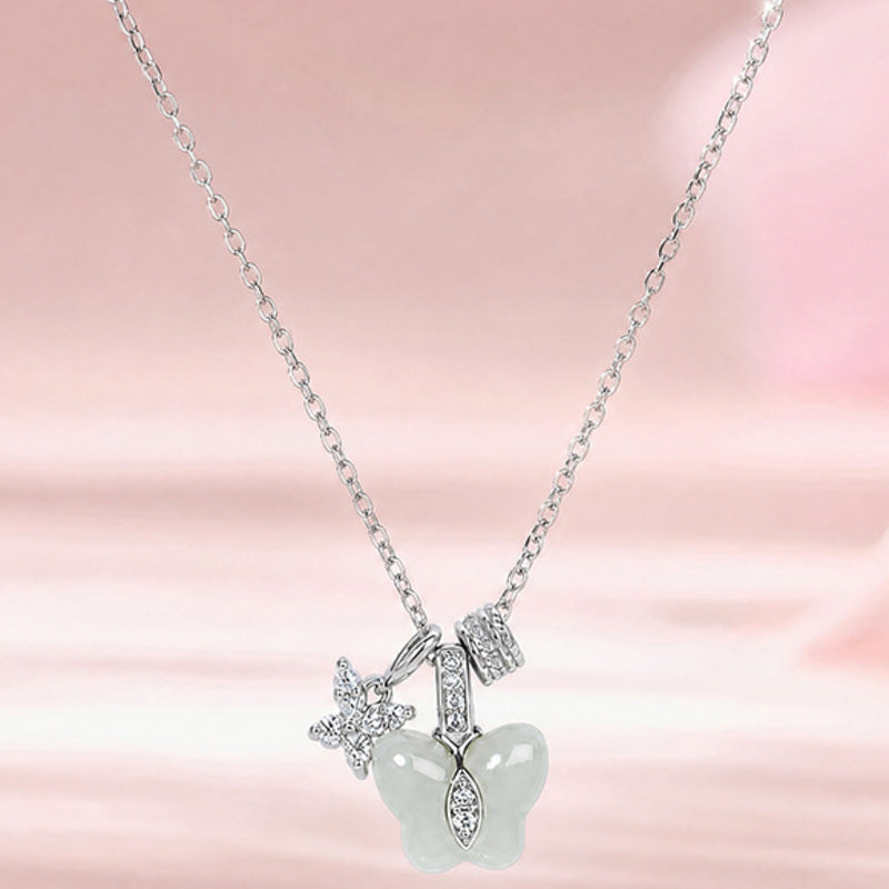 Greenish-white jade butterfly necklace on a soft pink background