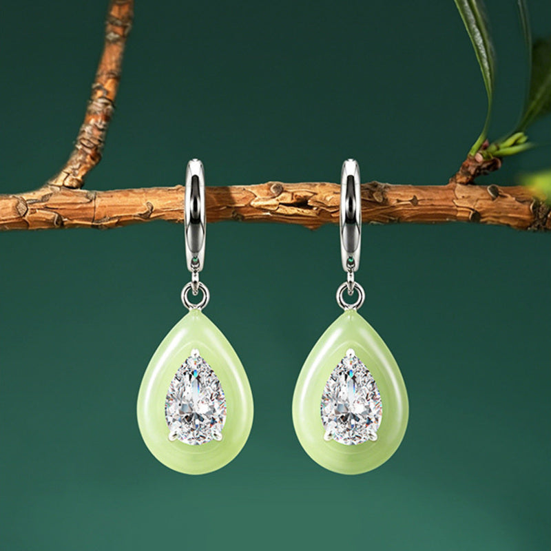 Greenish-white nephrite jade teardrop earrings on a dark green background
