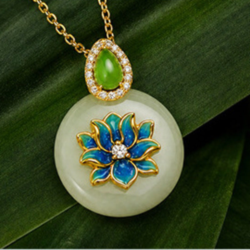 Centered front view of Hetian jade lotus peace buckle pendant on a green leaf
