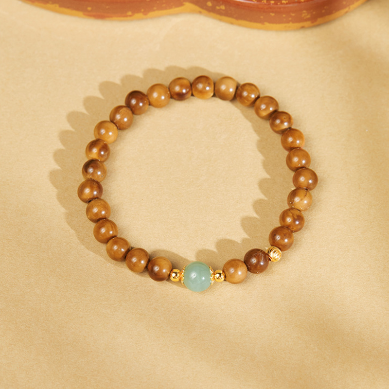 Kuka bead bracelet with centered green nephrite jade on warm backdrop