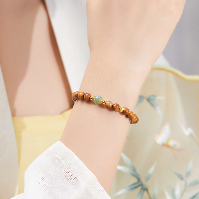 Close wrist view of brown Kuka and green jade bracelet