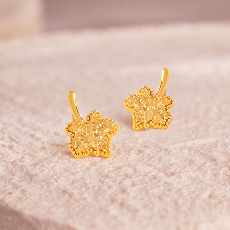 Pair of gold-tone sterling silver maple leaf studs on pale stone