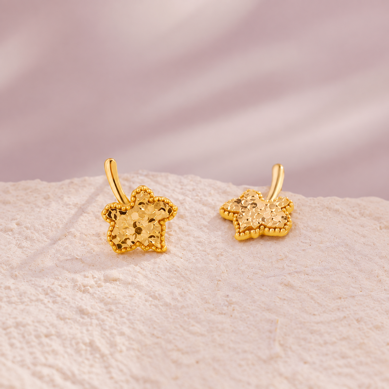 Angled view of maple leaf stud pair on pale stone