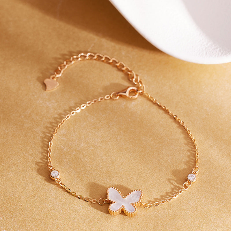 Mother-of-pearl butterfly bracelet arranged on warm gold background