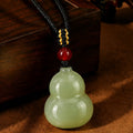 Nephrite jade gourd necklace centered on a warm dark background