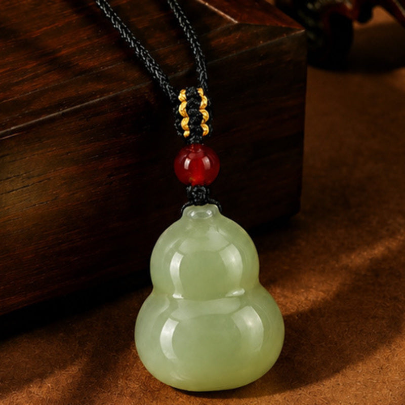 Nephrite jade gourd necklace centered on a warm dark background