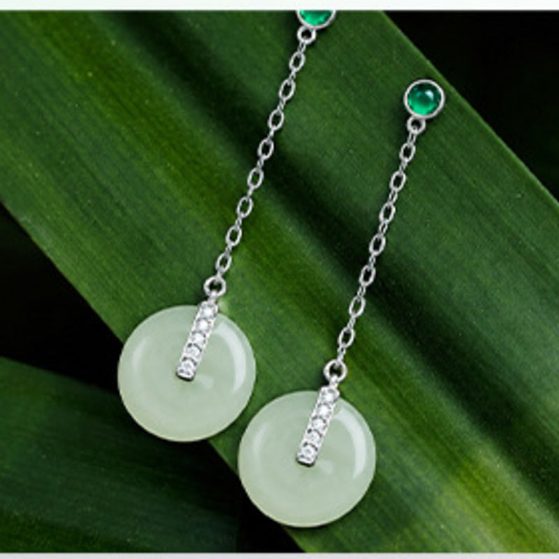 Nephrite jade peace buckle earrings displayed on green leaves