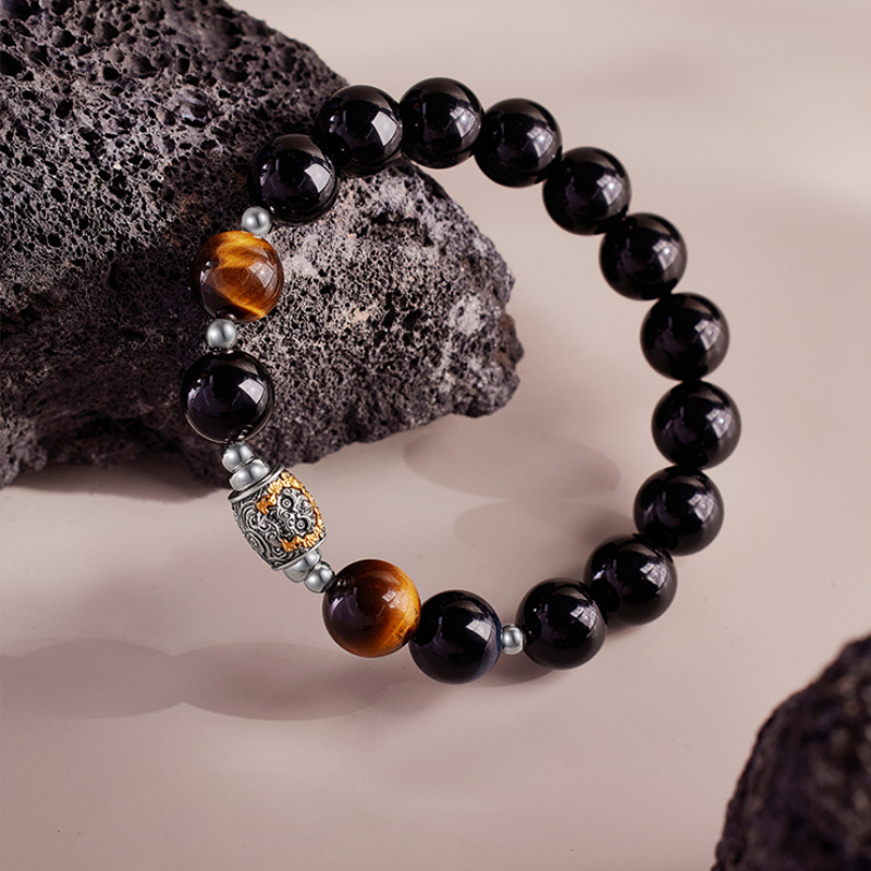 Obsidian Qilin bracelet resting against a dark rock