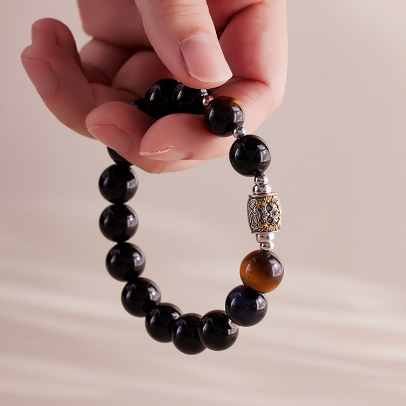Hand holding the complete elastic obsidian bracelet